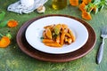 Garnish, fried glazed carrots on a white plate on a green concrete background. American cuisine. Vegan food