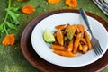 Garnish, fried glazed carrots on a white plate on a green concrete background. American cuisine. Vegan food