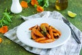 Garnish, fried glazed carrots on a white plate on a green concrete background. American cuisine. Vegan food