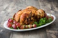 Garnished roasted turkey with grapes and herbs on a wooden table