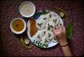 Garnishing idli and sambhar dish with curry leaves