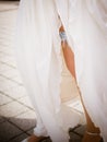 Garter on the leg of a bride, slim bride in wedding luxury dress showing her silk garter with golden ribbon Royalty Free Stock Photo