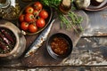 Garum fish sauce in a deep bowl with spices and tomatoes on a wooden table.