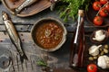 Garum fish sauce in a deep bowl with spices and tomatoes on a wooden table.