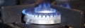 Gas burner on stove with blue fire at home closeup