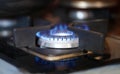 Gas burner on stove with blue fire at home closeup