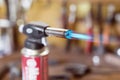 Gas cartridge gun lighter .Close-up nozzle of burner with blue flame jet. Workshop background, scorching of wood Royalty Free Stock Photo