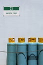 Gas cylinder tanks with safety first sign on white cement wall in safety zone area