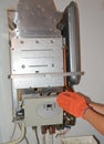 Gas heater maintenance and repair. A service man is cleaning, repairing, checking the settings during annual gas heater