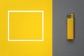 The lighter lies on a gray background next to a frame for text on a yellow background