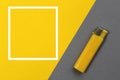 The lighter lies on a gray background next to a frame for text on a yellow background