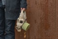 Gas mask in hand of person in black coat rusty corrosion wall background industry dirty abandoned environment concept poster