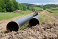 Gas pipeline laying on the countryside with two gas pipeline pipes in the foreground and machines for pipe laying along with other