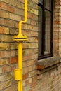 Gas reducer with yellow pipe along the wall of a house Royalty Free Stock Photo