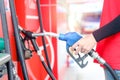 Gas station attendant in red uniform holding a fuel petrol pump nozzle against at gas station Royalty Free Stock Photo