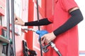 Gas station attendant in red uniform holding a fuel petrol pump nozzle against at gas station Royalty Free Stock Photo