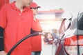 Gas station attendant in red uniform holding a fuel petrol pump nozzle against for filling up the car with petrol at gas station Royalty Free Stock Photo