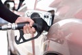 Gas station worker with black sunscreen arm sleeve filling up bronze pickup truck tank. Closeup hand holding black gas pump nozzle Royalty Free Stock Photo