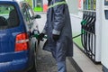 A gas station worker inserts a gas pistol into a car tank. Dolyna, Ukraine - May 12, 2020