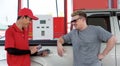 Gas station worker in red uniform stand smiling, swipe mockup credit card via payment terminal. Caucasian driver with sunglasses