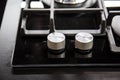 Gas stove burner knobs with black mirror surface of cooker and stainless steel grills. Top view, close up Royalty Free Stock Photo