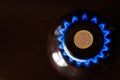 gas stove burner with one euro coin laid on top, burning natural gas with blue flame Royalty Free Stock Photo