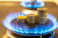 Gas cooking stove on, with coins. Gas cost. Royalty Free Stock Photo