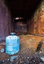 A gas tank sits inside an old rusty dumpster