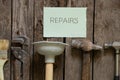 Gas wrench hammer plunger and brush lie on a wooden table in the kitchen and the word on paper in English repair