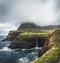 Gasadalur village and Mulafossur its iconic waterfall, Vagar, Faroe Islands, Denmark. Rough see in the north atlantic