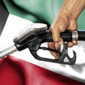 Gasoline consumption concept - Hand holding hose against flag of Kuwait Royalty Free Stock Photo