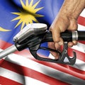 Gasoline consumption concept - Hand holding hose against flag of Malaysia Royalty Free Stock Photo