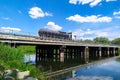 A gasoline or gas tanker truck transports fuel to a gas station through a river bridge on a sunny day