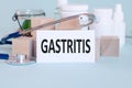 GASTRITIS - text on card on wooden table with stethoscope medical pills and wooden blocks