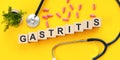 GASTRITIS word written on wooden blocks and stethoscope on light yellow background