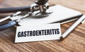 Gastroenteritis written on label tag with pen and Stethoscope on wood background