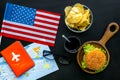 Gastronomical tourism with american flag, passport, tickets, map, burgers, chips, coke on black background top view Royalty Free Stock Photo