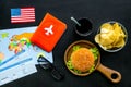 Gastronomical tourism with american flag, passport, tickets, map, burgers, chips, drink on black background top view Royalty Free Stock Photo