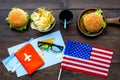 Gastronomical tourism with american flag, passport, tickets, map, burgers, chips, drink on wooden background top view Royalty Free Stock Photo