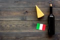 Gastronomical tourism. Italian food symbols. Italian flag, cheese parmesan and bottle of red wine on dark wooden Royalty Free Stock Photo