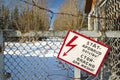 At the gate with barbed wire is a sign with lightning `stand - life threatening!` Forgotten, abandoned ghost town Skrunda, Latvia.