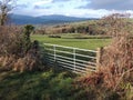 Gate, farm, in winter sunlight, with distant hills.