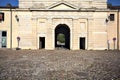 Gate of a fortification on a cobbled square of an italian town at sunset Royalty Free Stock Photo