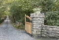 Gate post with wooden gate open to a long driveway Royalty Free Stock Photo