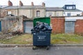 Gateshead UK: An overfull wheelie bin in grimy back alley in Northern England