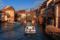 Gateway on river Ill and tourist boat on background of traditional half-timbered houses in Strasbourg.