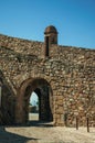 Gateway in wall made of rough stone with watchtower