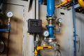 Gauges in the boiler room near the heating pipes with insulation coating.