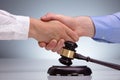 Gavel In Front Of Two Men Shaking Hands Royalty Free Stock Photo