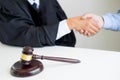 Gavel hammer Justice on wooden table with judge and client shaking hands after adviced in background at courtroom, lawyer service Royalty Free Stock Photo